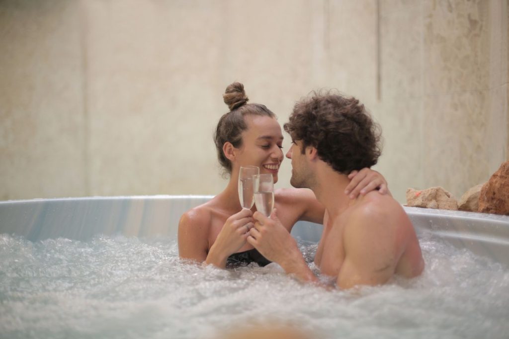 pexels-photo-3852263 Cheerful young man and woman enjoying time together sitting in round bath with water babbles while drinking champagne and looking at each other with love in spa center during weekend